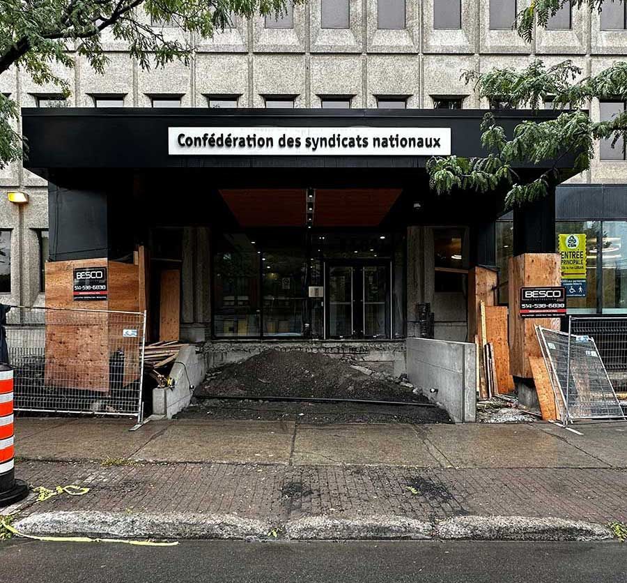 The entrance to the Confédération des syndicats nationaux building, currently under renovation with plywood hoardings.