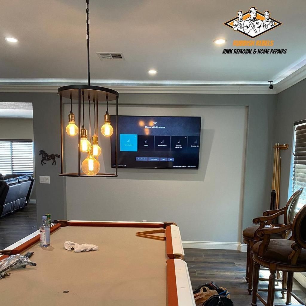 Modern living room with pool table, wall-mounted TV, hanging pendant lights, and seating area
