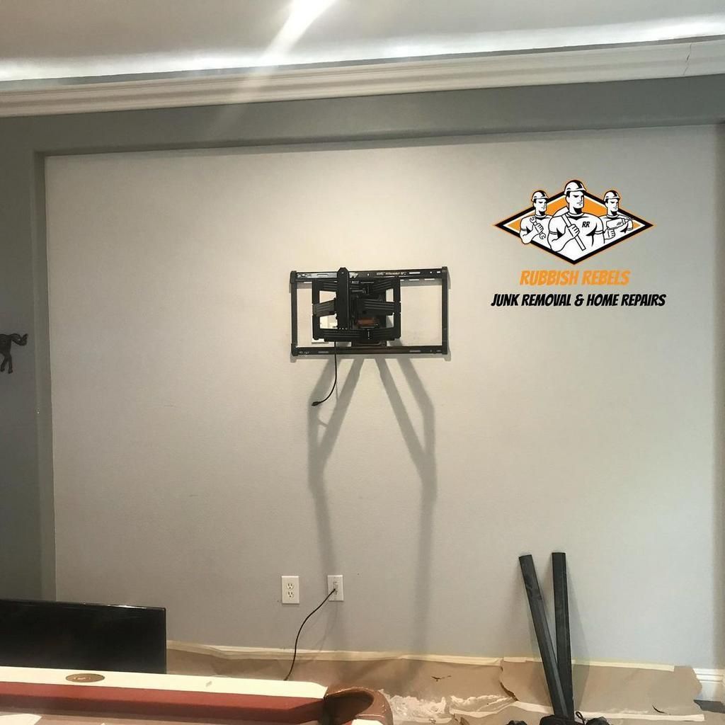 Empty room with wall-mounted TV bracket, exposed cables, and logo on the right wall