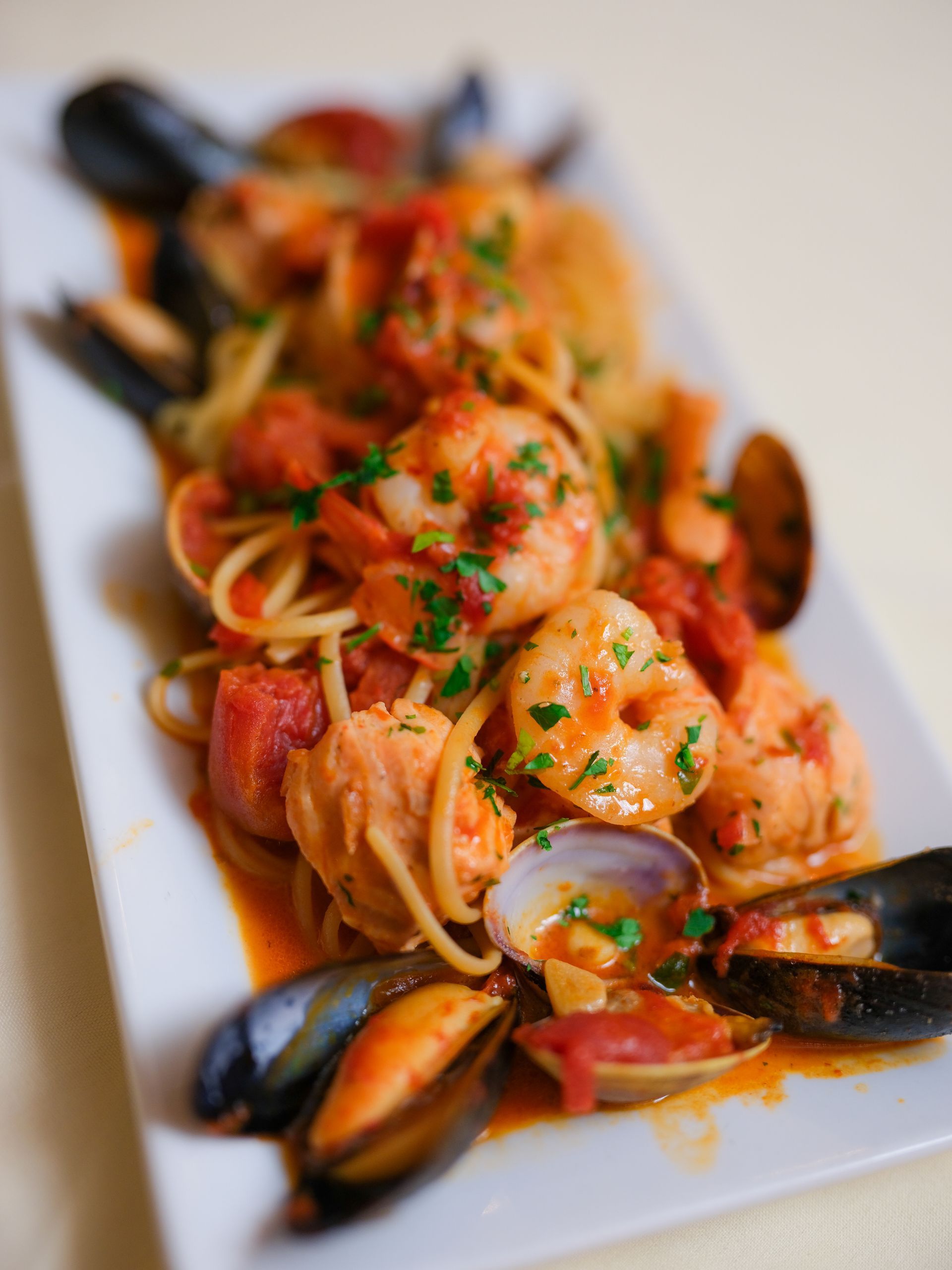 A white plate topped with shrimp mussels and noodles