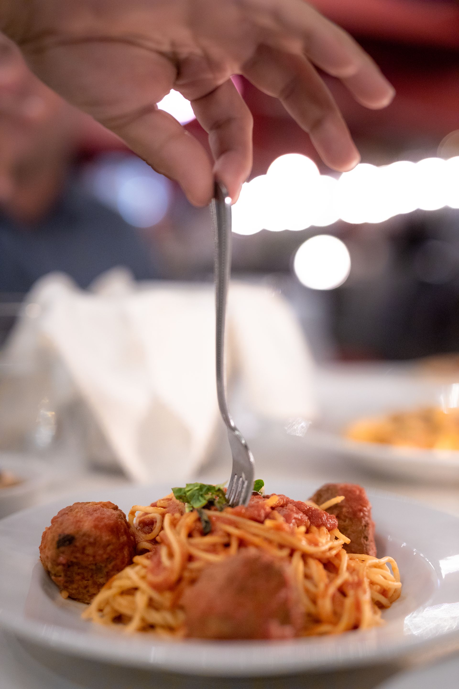 A person is holding a fork over a plate of spaghetti and meatballs.