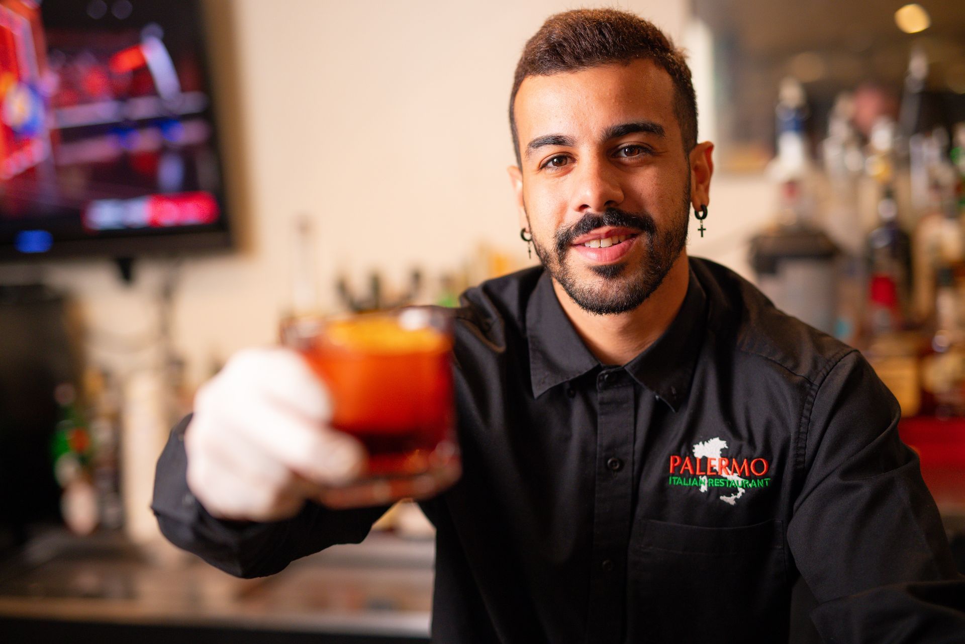 A man in a black shirt is holding a drink in his hand.