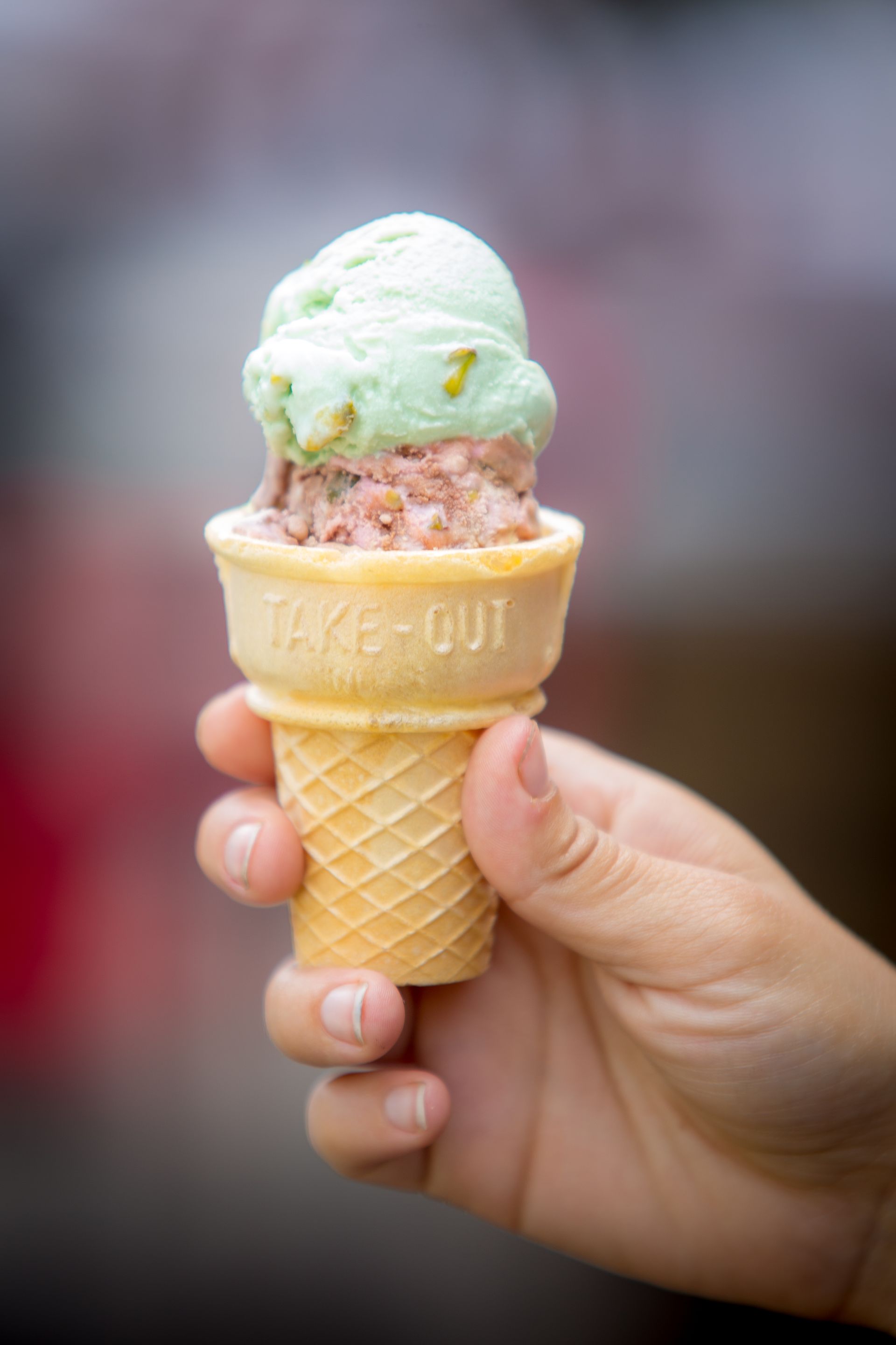 A person is holding an ice cream cone with two scoops of ice cream in it.