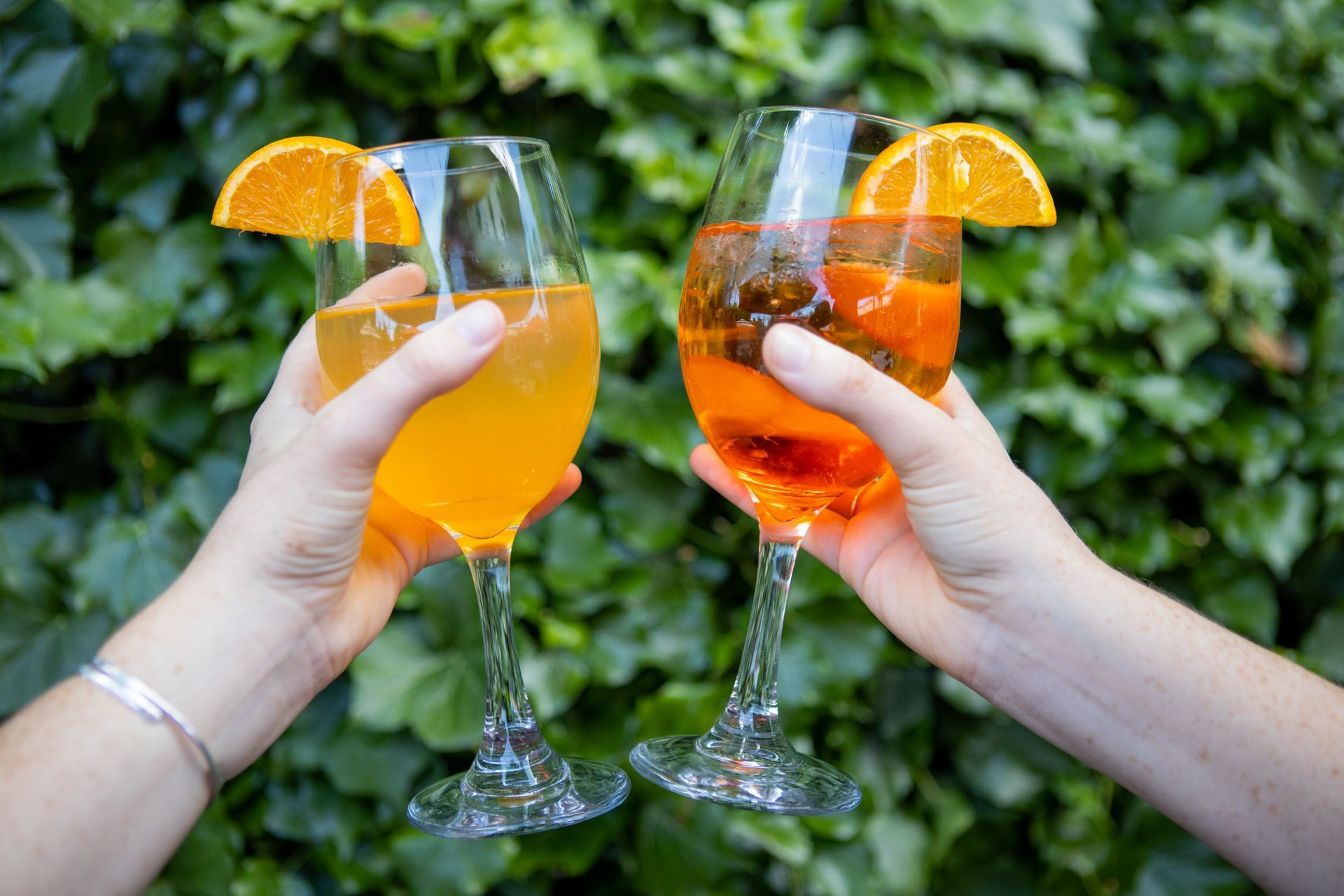 Two people are toasting with two glasses of orange juice.