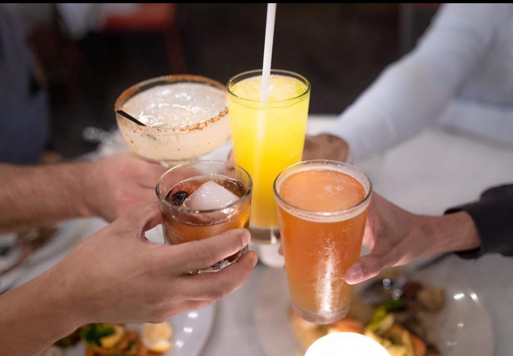 A group of people are toasting with drinks at a table.