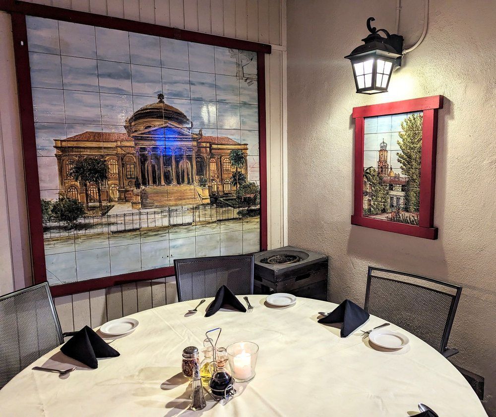 A dining room with a round table and a painting on the wall.