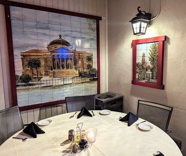 A dining room with a round table and a painting on the wall.