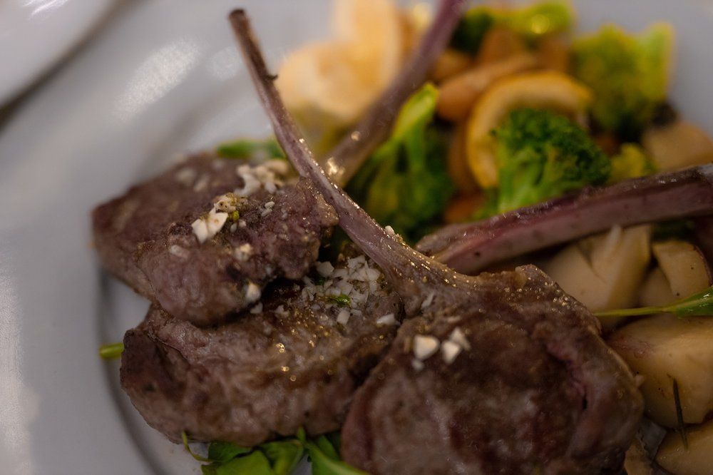 A close up of a plate of food with meat and vegetables on a table.