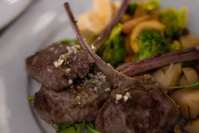 A close up of a plate of food with meat and vegetables on a table.