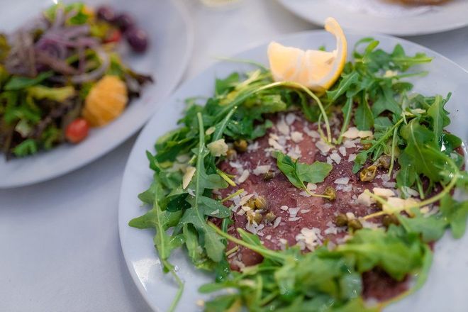 A close up of a plate of food with a salad on a table.