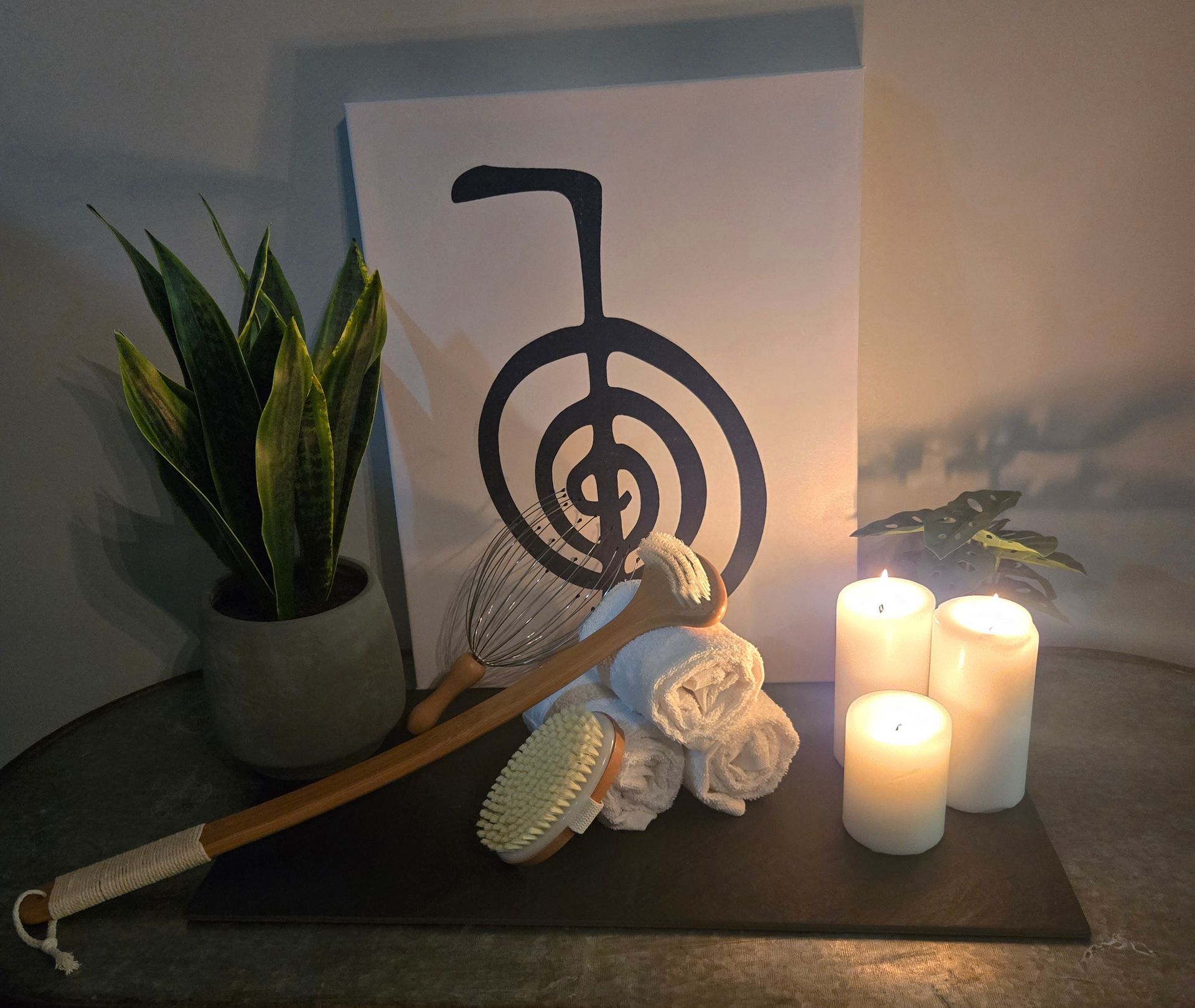 Reiki-themed spa scene: candles, rolled white towels, back massager, plant, drawing of symbol.