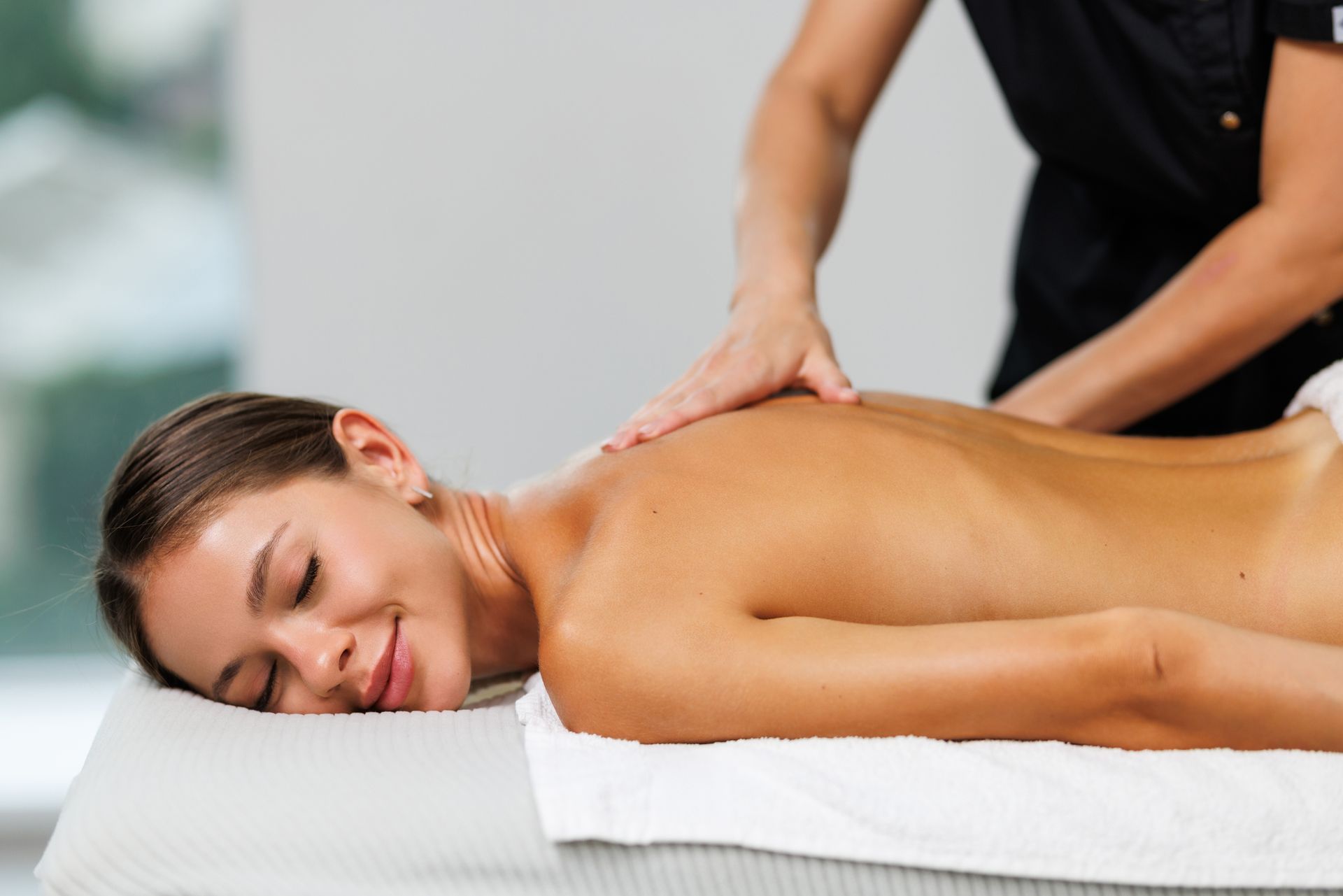 Woman receiving a back massage on a white table in a spa setting