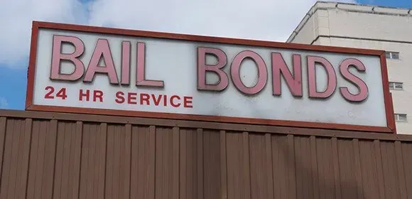Bail bonds sign with “24 HR SERVICE” on a building roofline