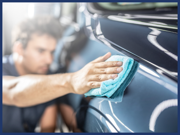 A person uses a cloth to polish and wipe down the shiny vehicle.