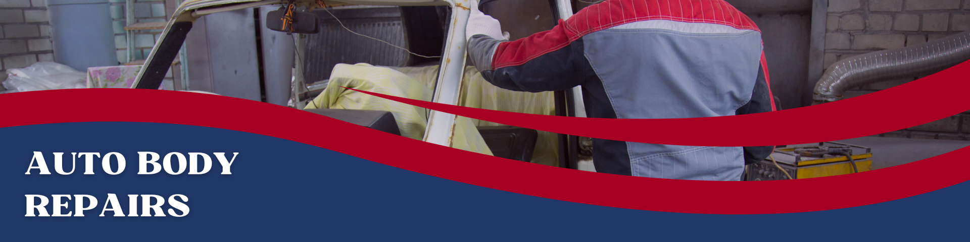 A person wearing a jacket works on the body of a car in an auto shop.