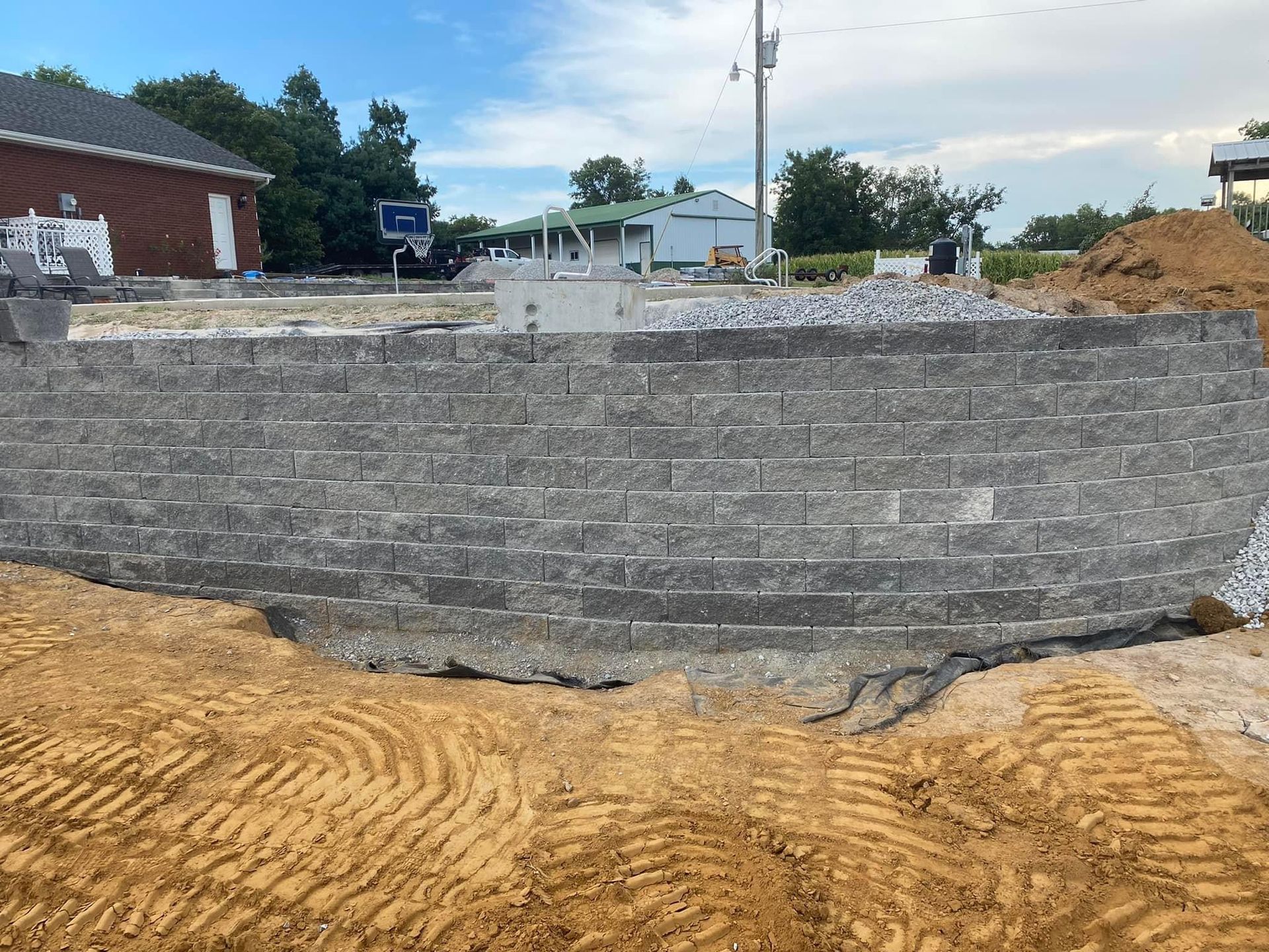 A brick wall is being built in a dirt field.