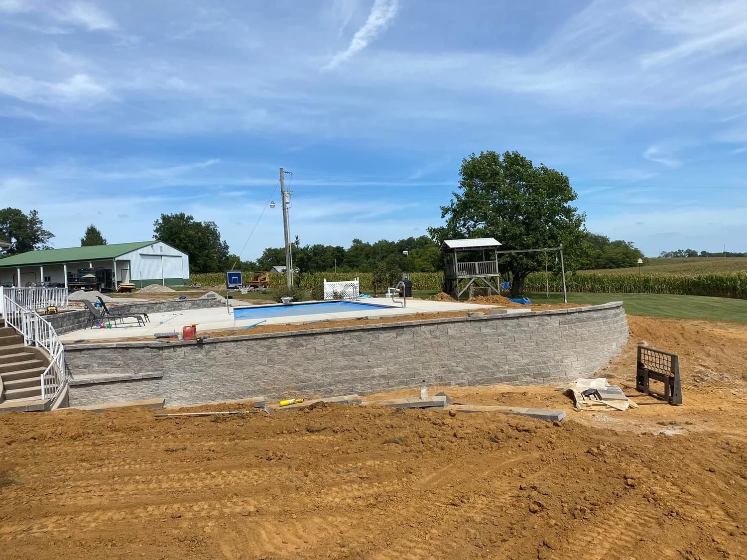 A large swimming pool is being built in the middle of a dirt field.
