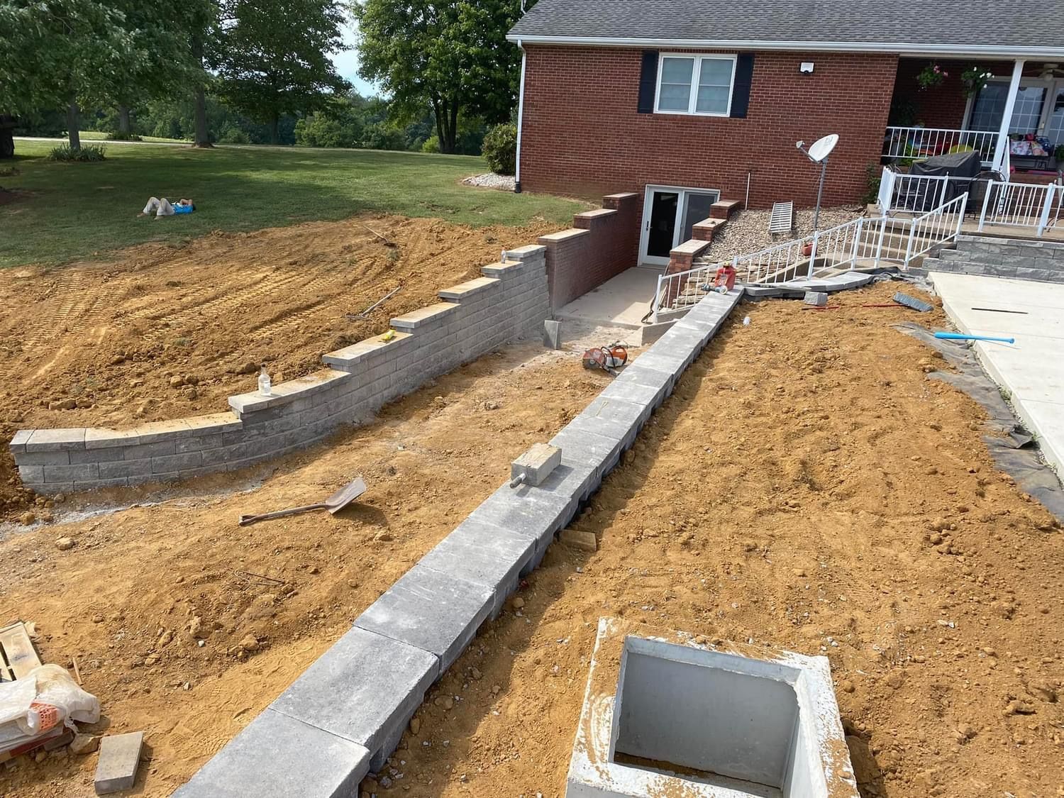 A brick house is being built in the middle of a dirt field.
