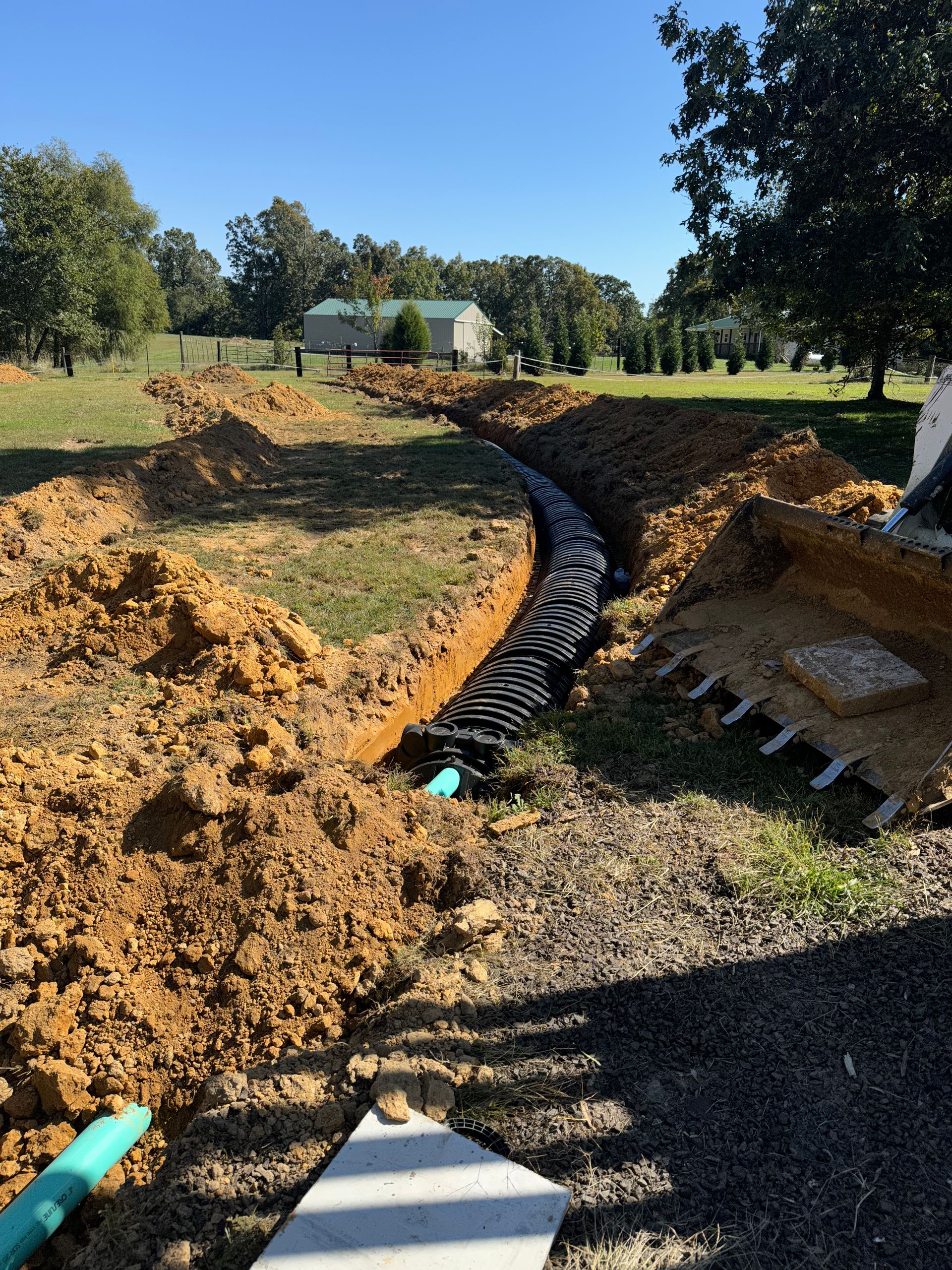 A drainage system is being installed in a dirt field
