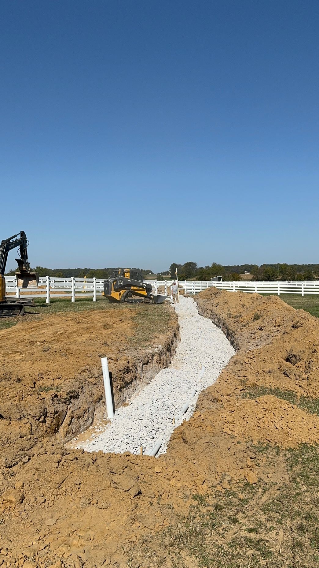 A bulldozer is digging a trench in the dirt in a field.