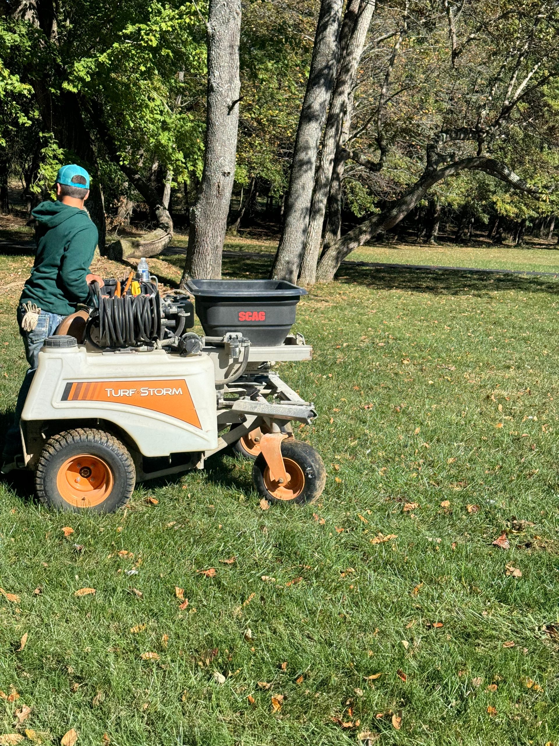 A man is riding a lawn mower in a park.