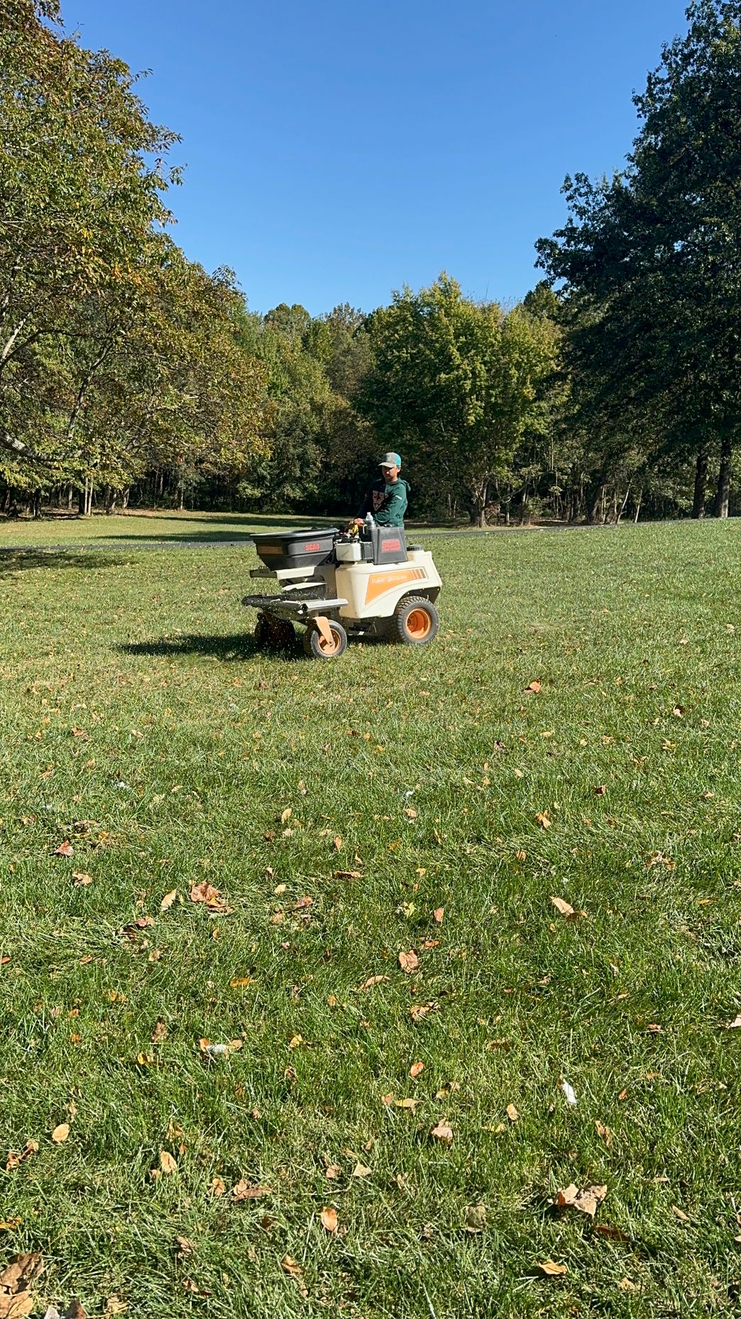 A person is riding a lawn mower on a lush green field.