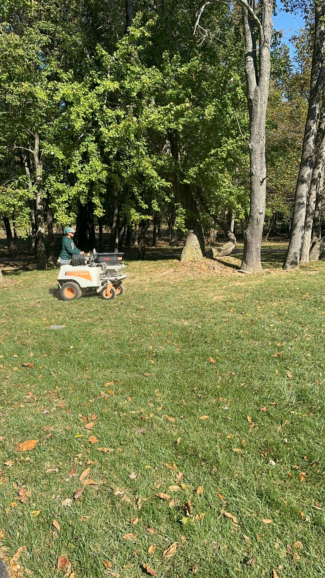 A person is riding a lawn mower in a park.