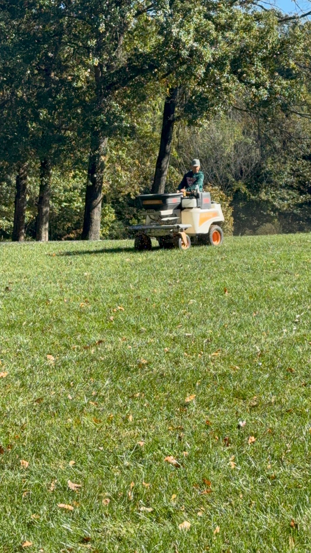 A person is riding a lawn mower on a lush green field.