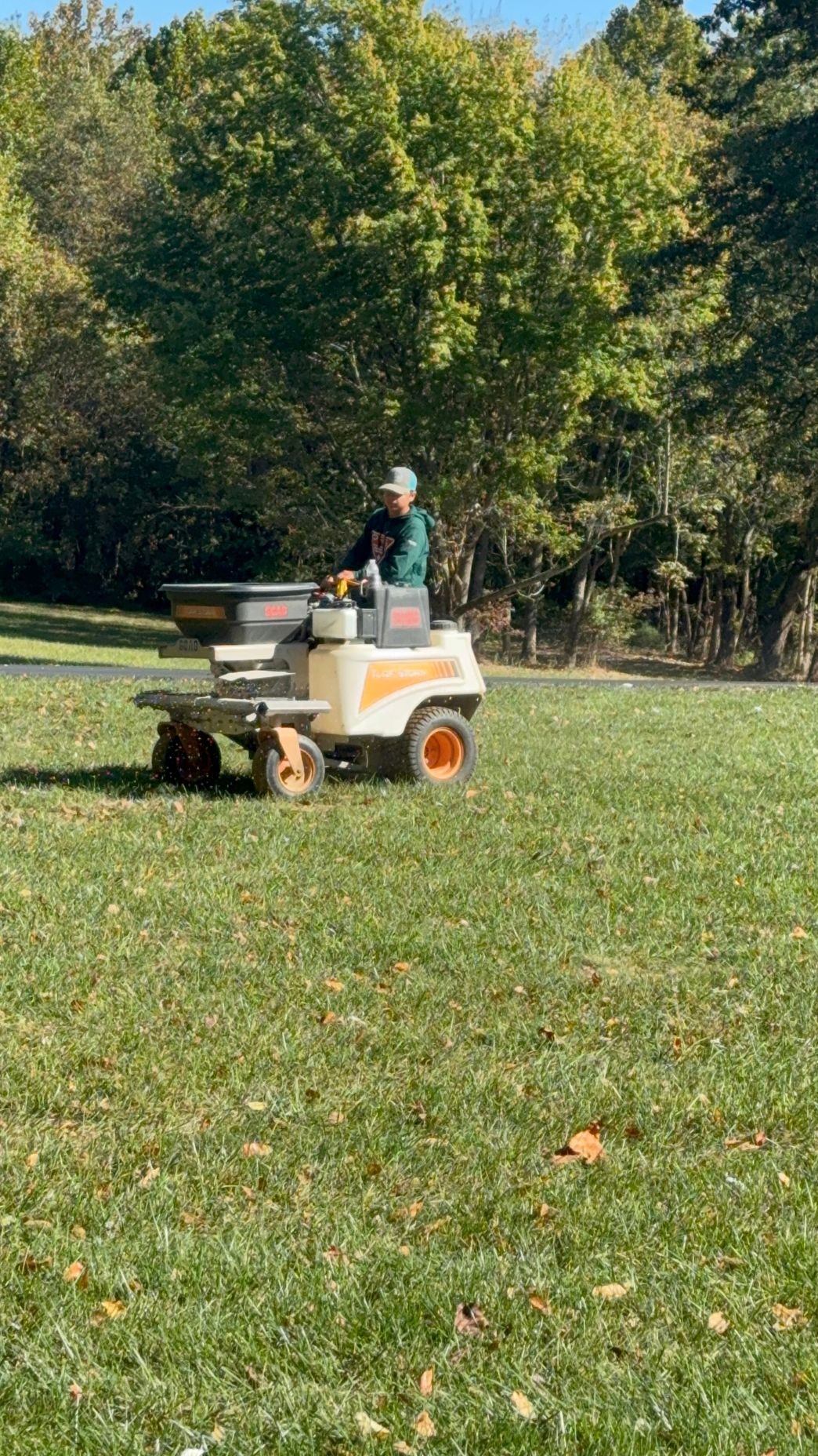 A man is riding a lawn mower in a park.