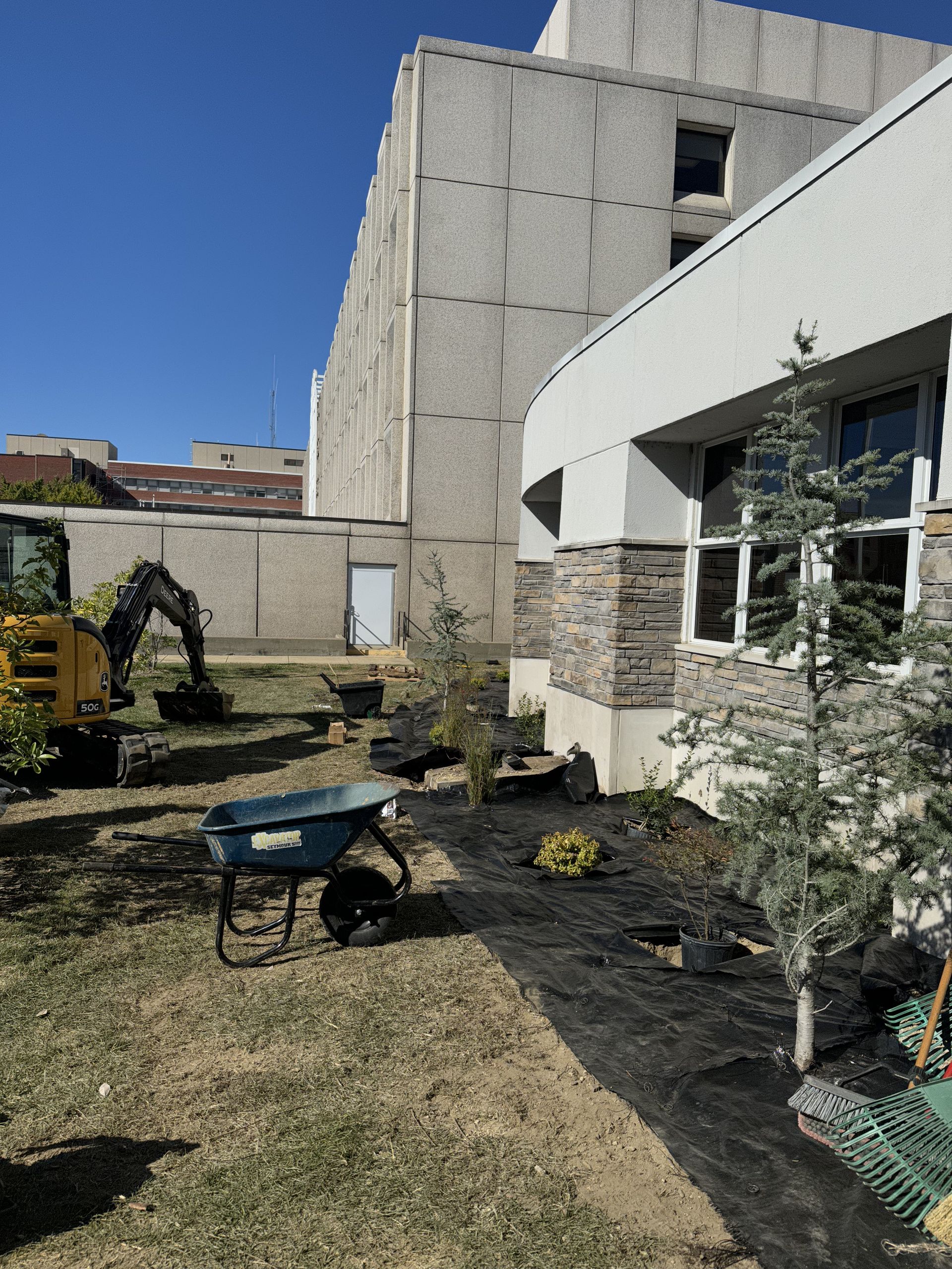 A wheelbarrow is sitting in the grass in front of a building.