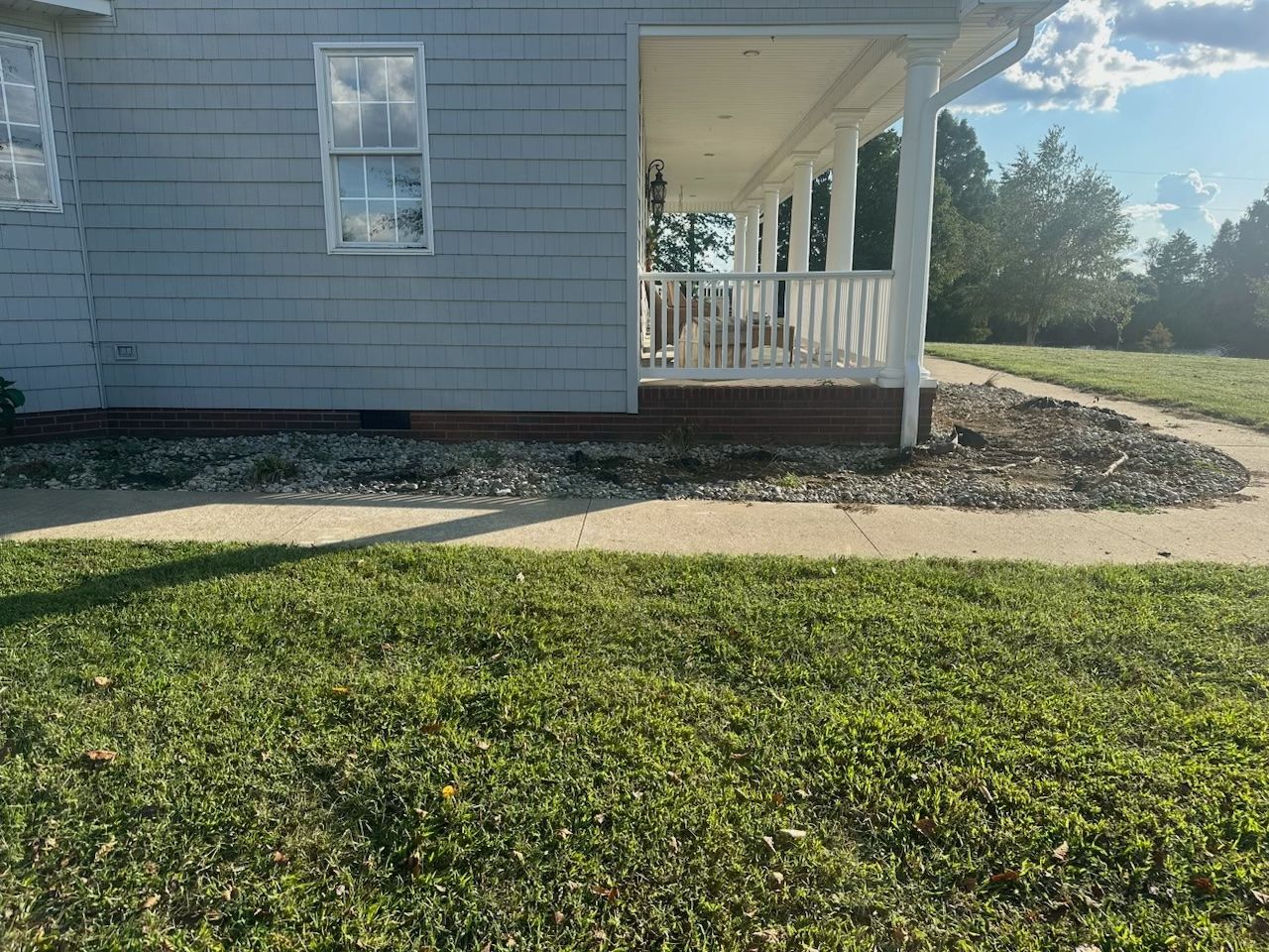 A house with a porch and a lawn in front of it.