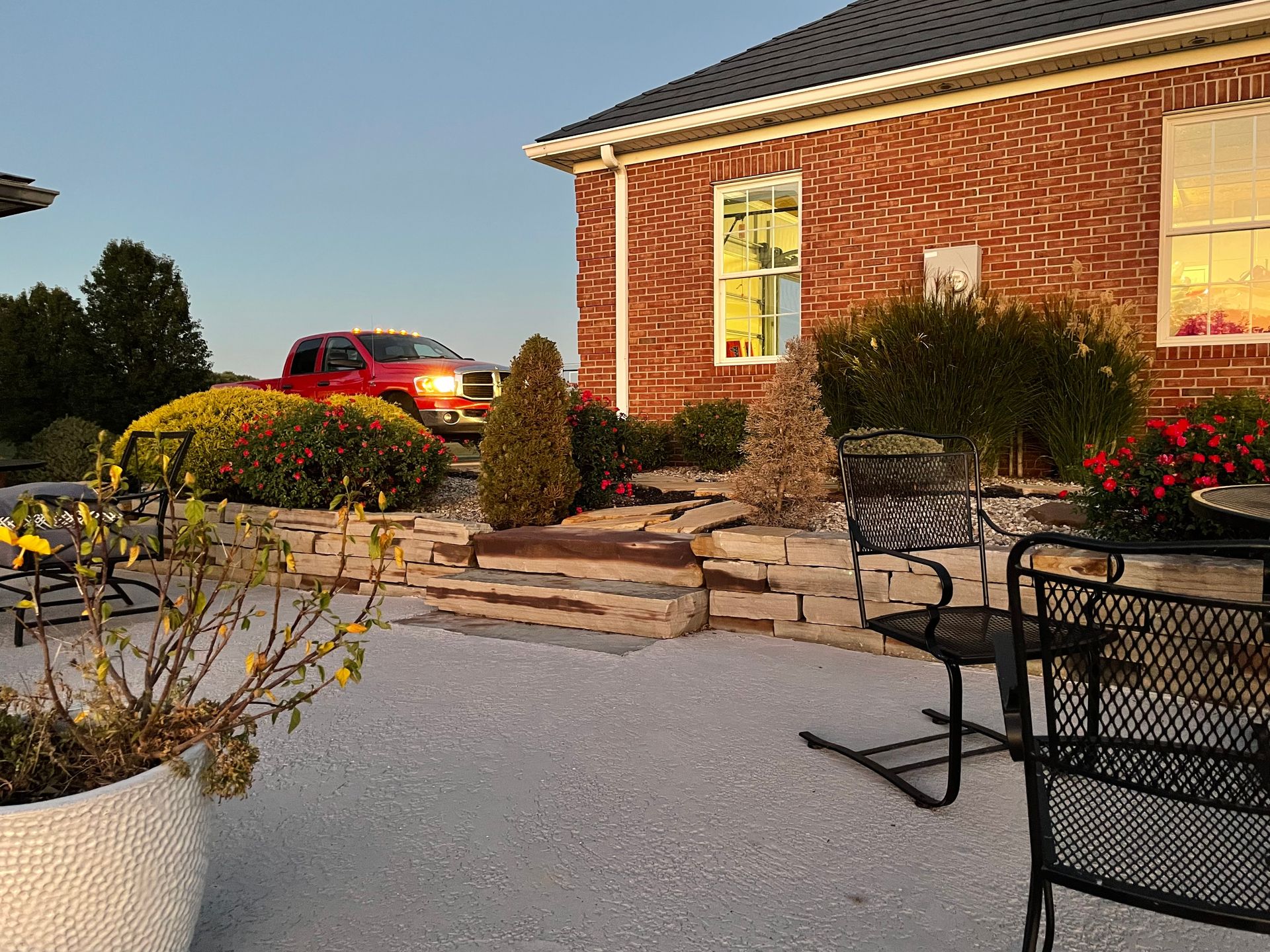 A red truck is parked in front of a brick house
