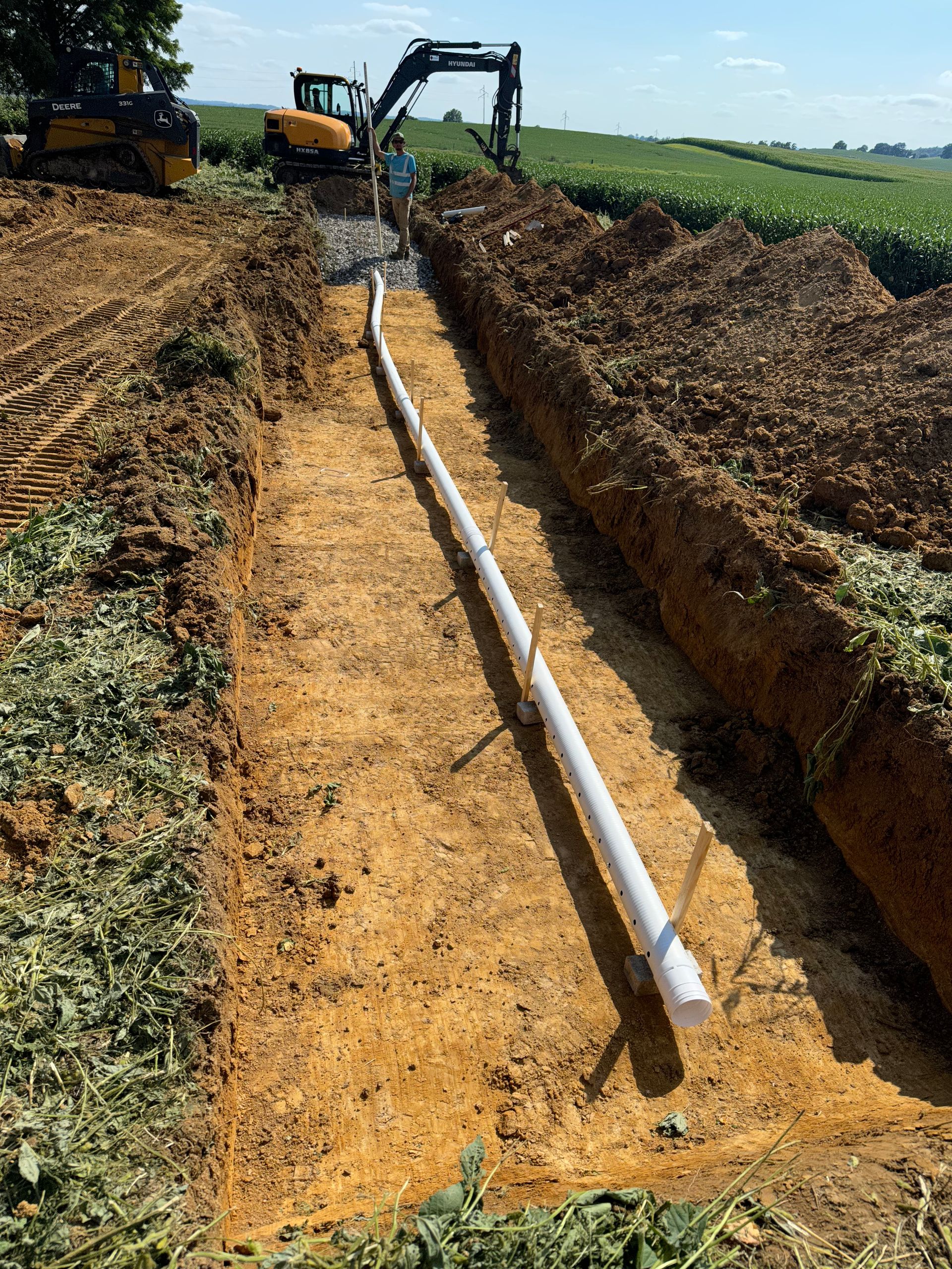 A pipe is being installed in the dirt in a field.
