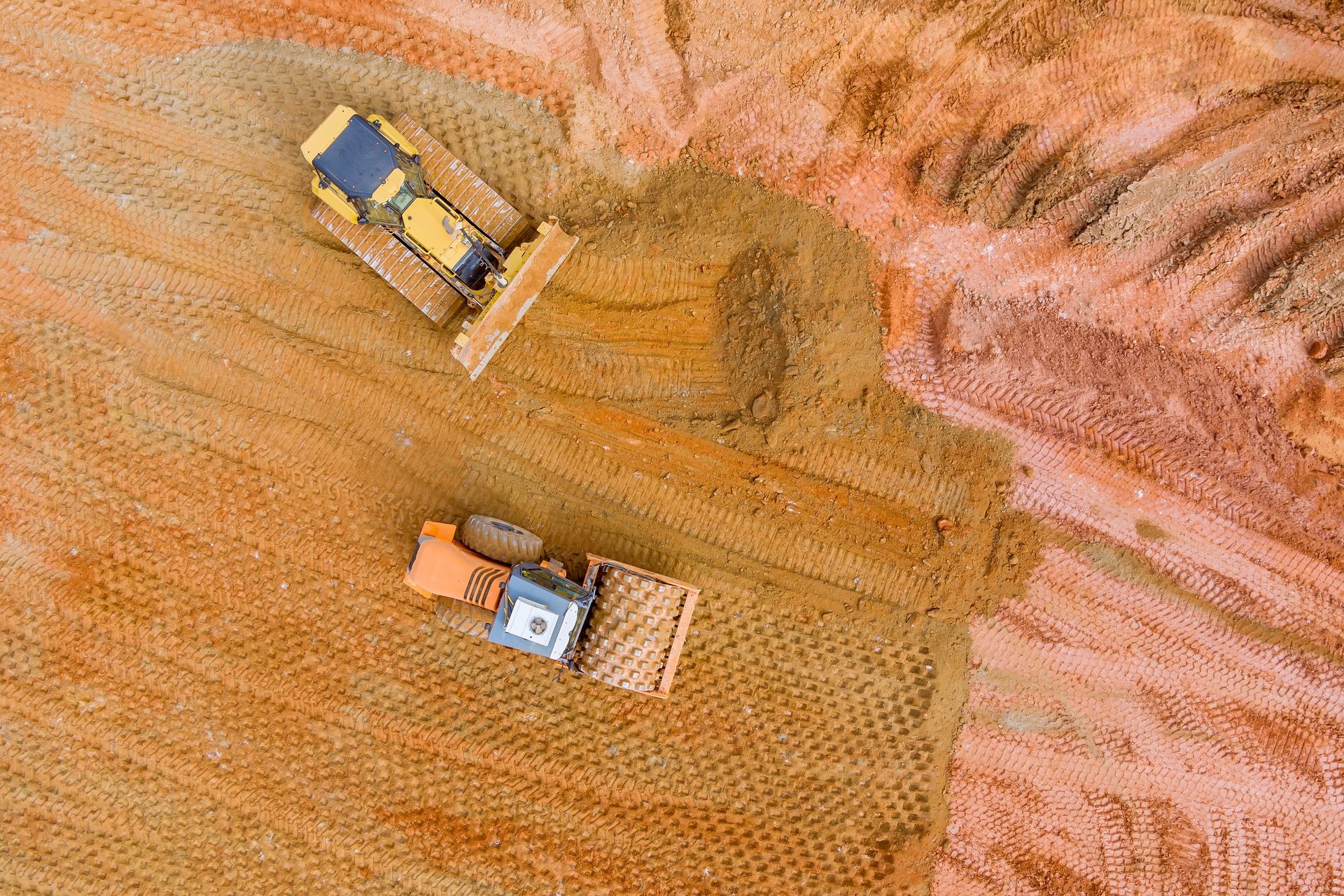 An aerial view of two bulldozers working on a dirt field.