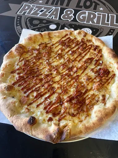 Cheesy flatbread pizza with caramelized drizzle on a plate at a pizza and grill restaurant