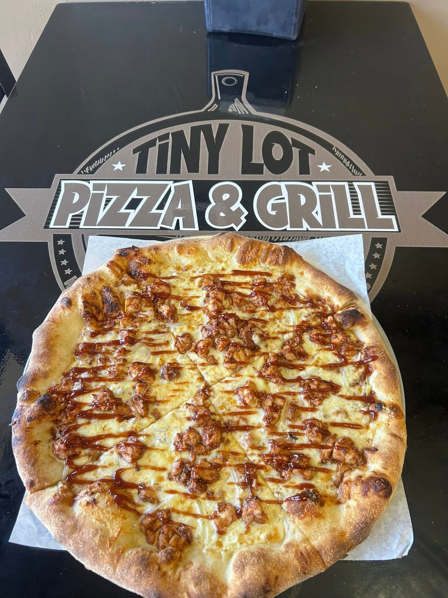 Pepperoni pizza in a box from Tiny L’s Pizza & Grill, with logo visible above it