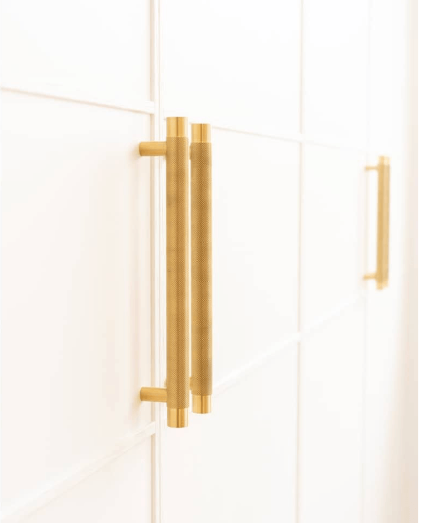 A Close Up of a Pair of Gold Cabinet Handles on a White Cabinet — Paiano Custom Kitchens In Corrimal, NSW