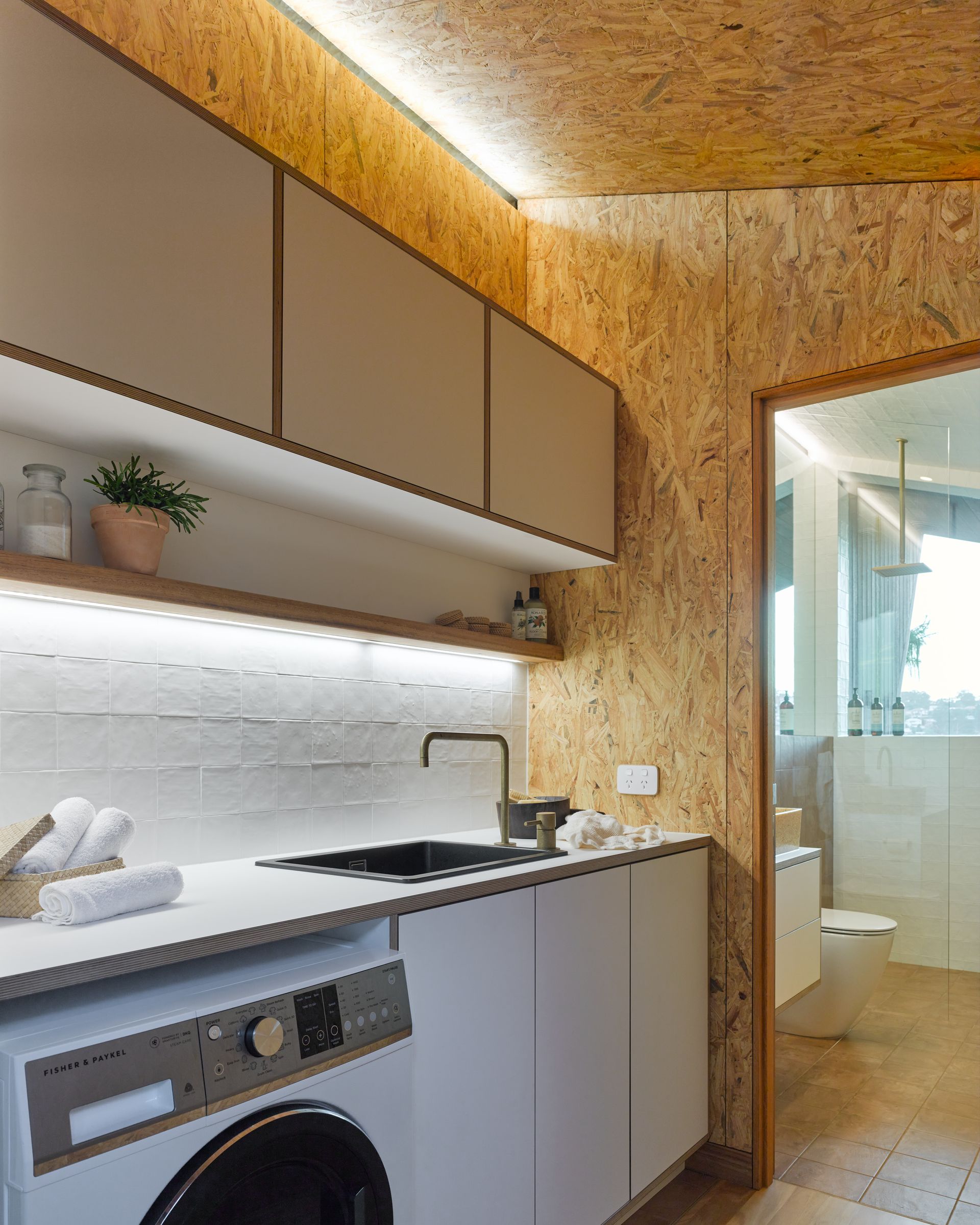A modern laundry with cork walls and bathroom in background — Paiano Custom Kitchens In Corrimal, NSW