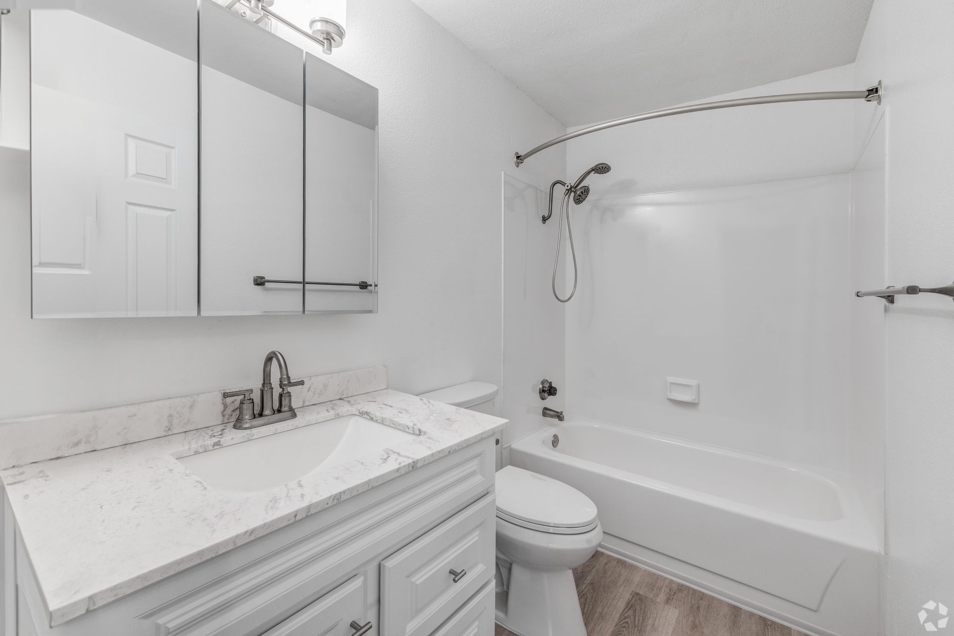 White bathroom with a sink, toilet, and shower/tub.