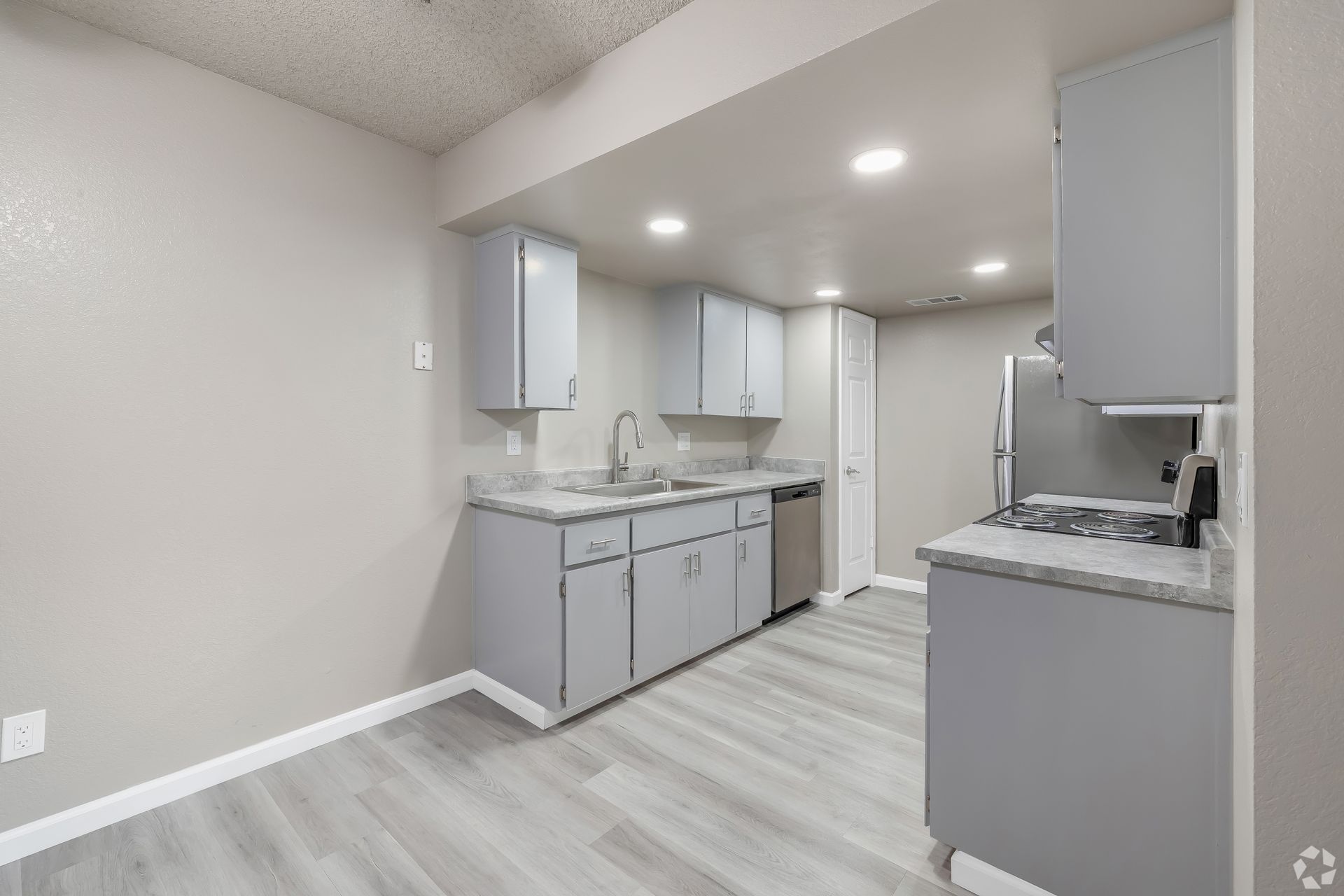 Gray kitchen with cabinets, countertops, and appliances, with light-colored flooring.
