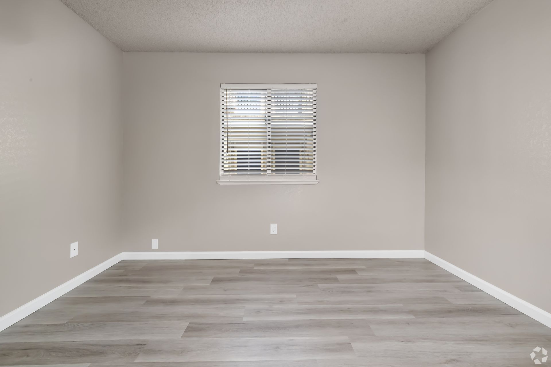 Empty room with gray walls, flooring, window with blinds.