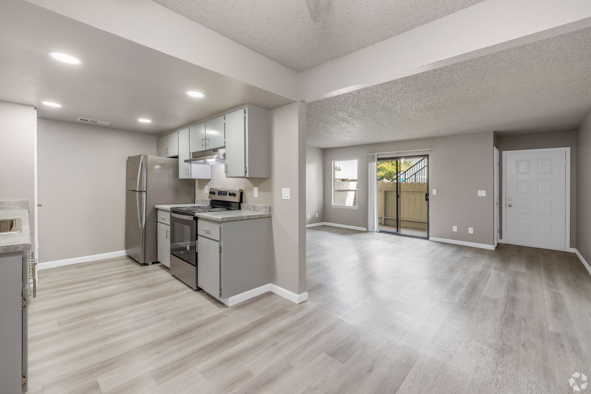Kitchen and living room with gray walls, stainless steel appliances, and sliding glass door to patio.