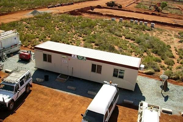 An aerial view of a demountable building in a construction site with vehicles.