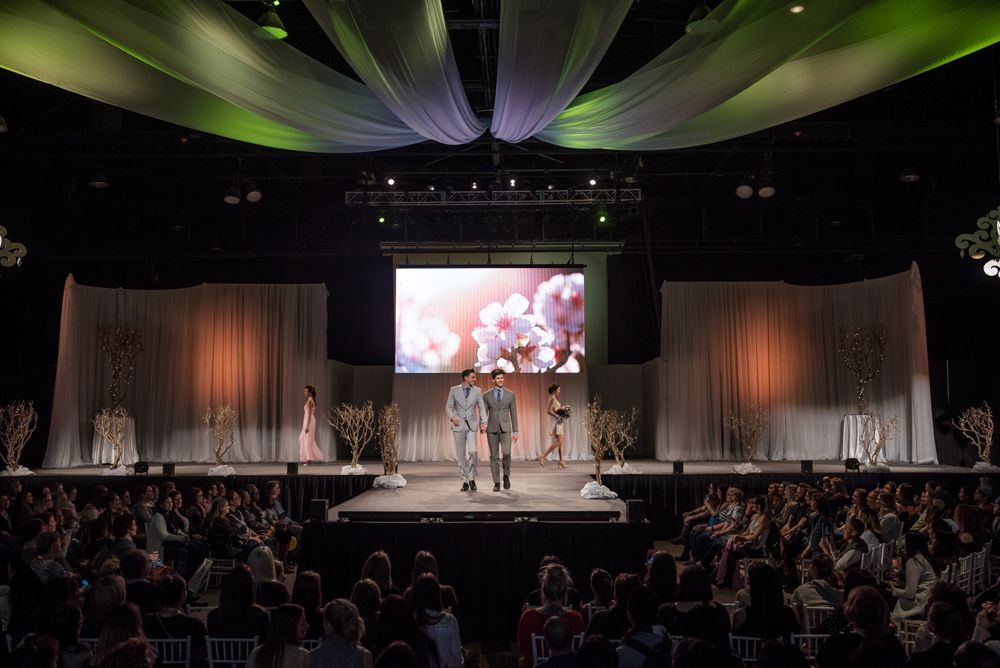 A group of people are standing on a stage in front of a large screen.