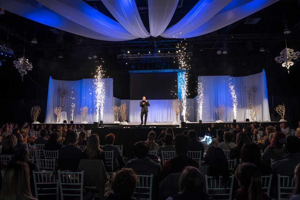 A man is standing on a stage in front of a crowd of people.