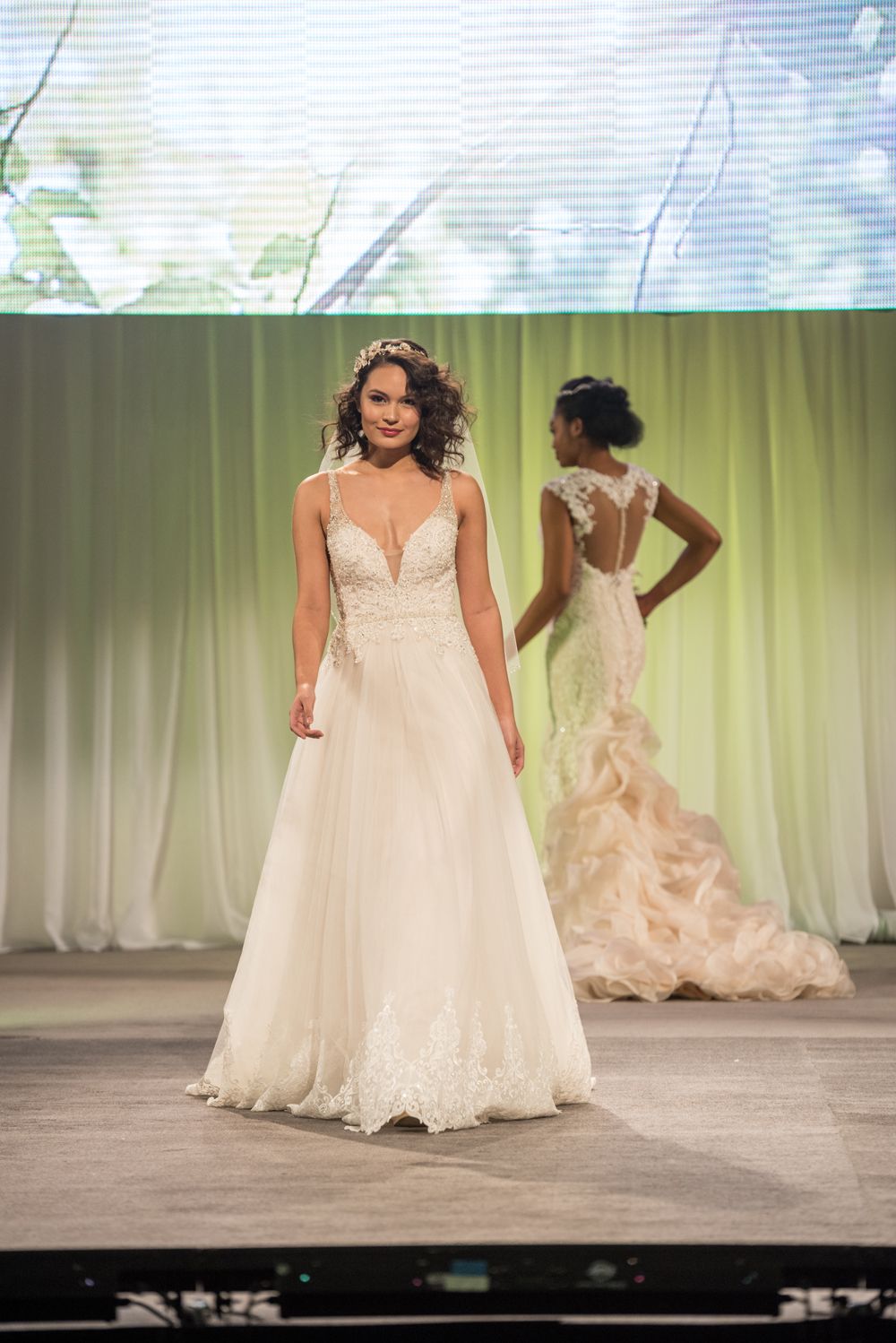 A woman in a wedding dress is walking down a runway.