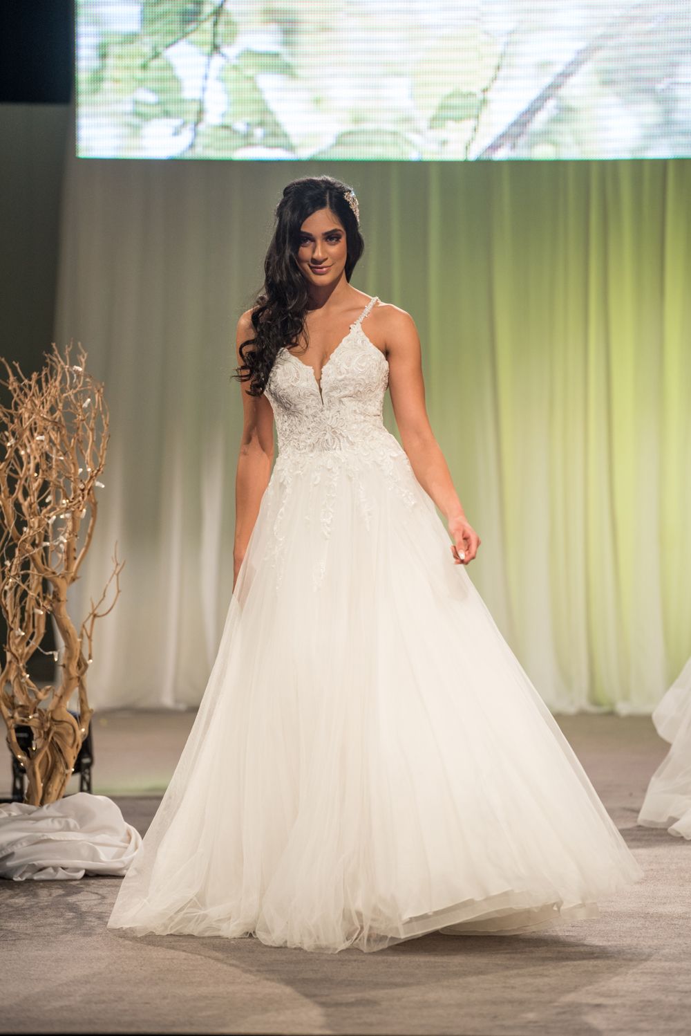 A woman is walking down a runway wearing a wedding dress.