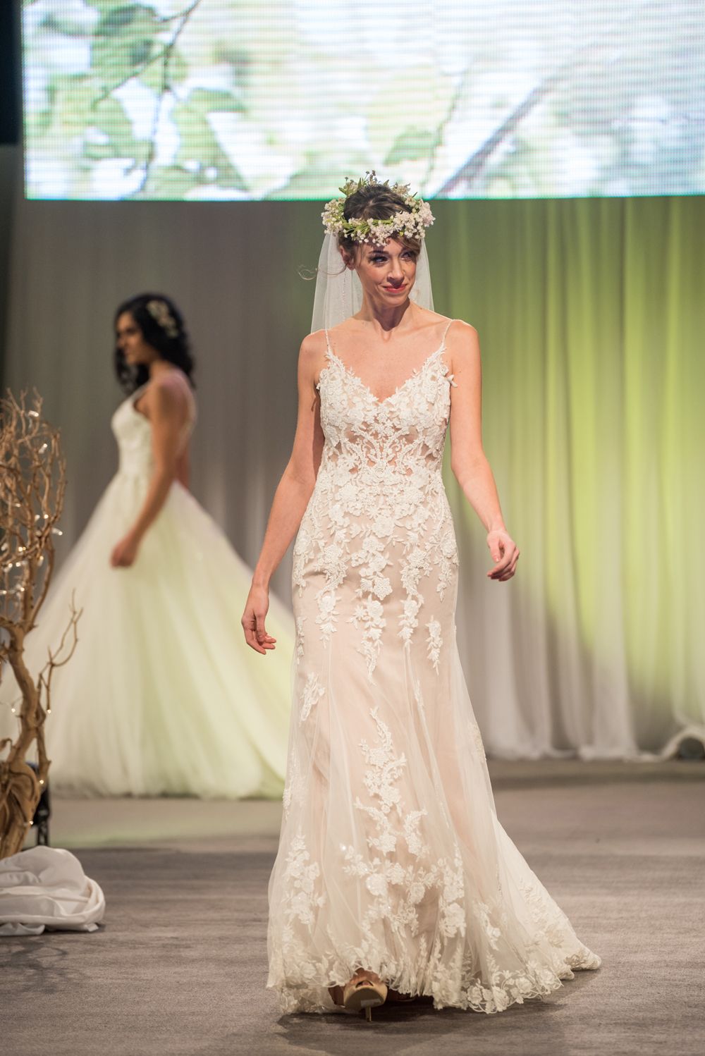 A woman in a wedding dress is walking down a runway.