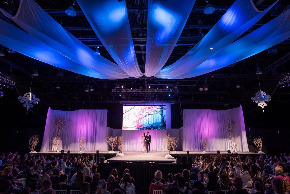 A man is standing on a stage in front of a crowd.