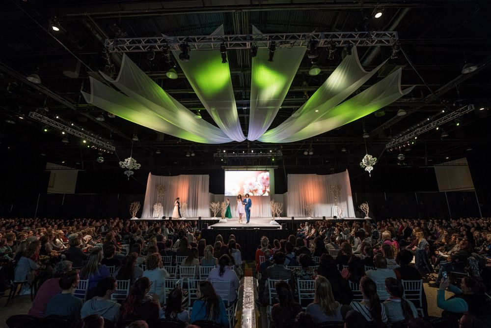 A large group of people are sitting in front of a stage at a convention.